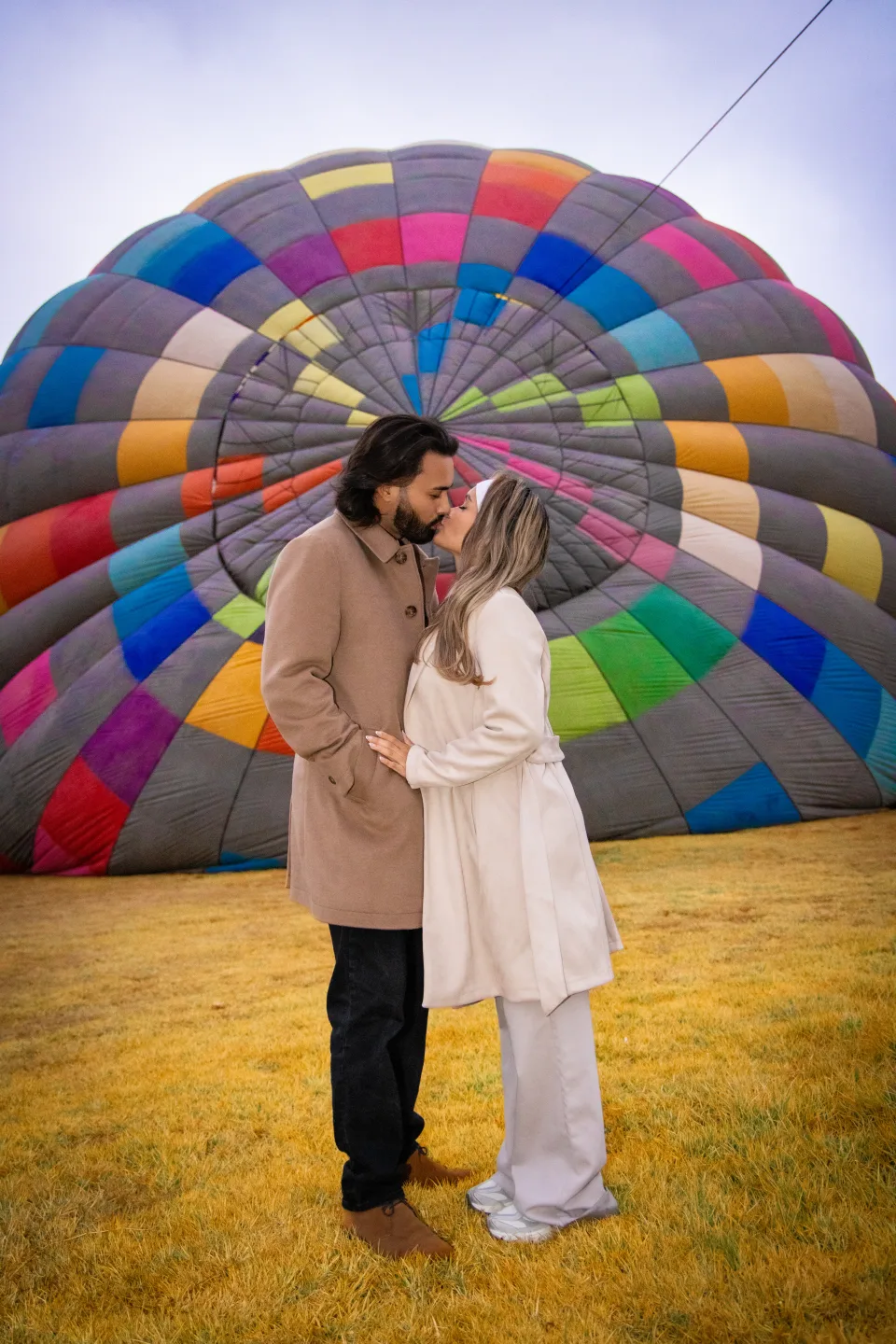 Pareja a punto de besarse frente a un colorido globo en el campo