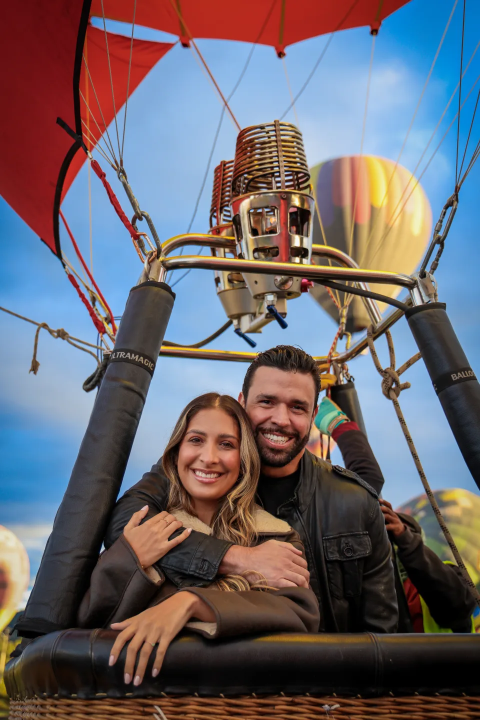 Pareja abrazada dentro de la canastilla del globo al amanecer en Teotihuacán