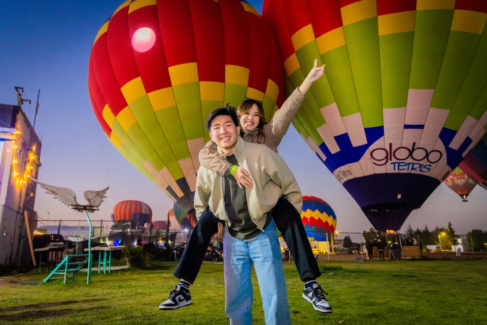 Pareja a caballito con vibrantes globos encendidos y luces al amanecer