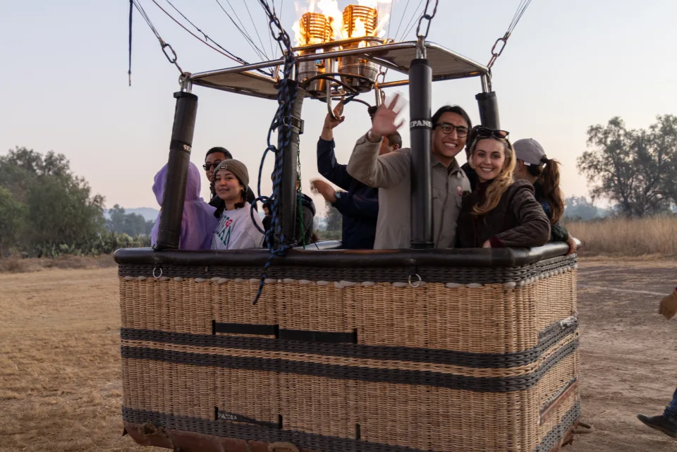 Pasajeros reales saludando desde la canastilla antes de un vuelo al amanecer sobre Teotihuacán