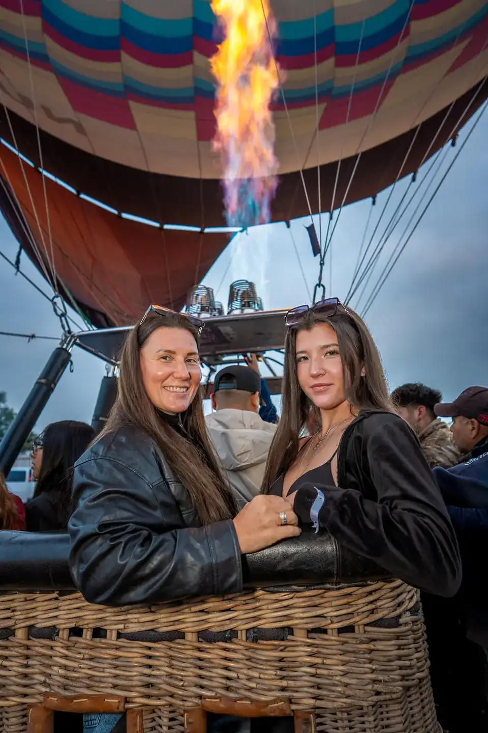 Teotihuacan hot air balloon ride: mother and daughter smiling in the basket as the burner fires at dawn