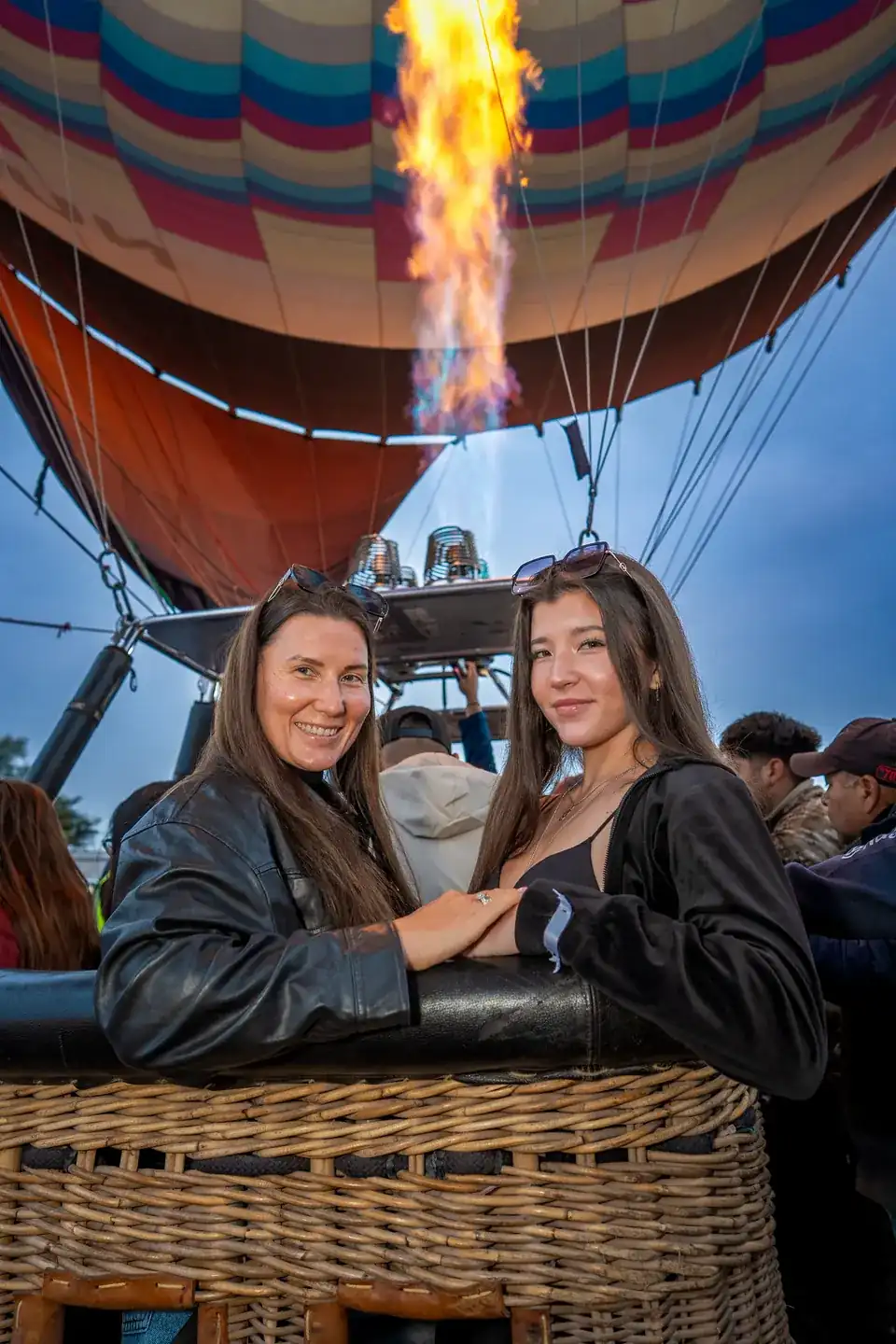 Mother and daughter together in the hot air balloon basket with the burner lit before takeoff