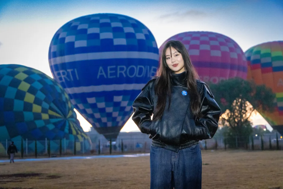 Mujer posando frente a un gran globo azul al amanecer en Teotihuacán