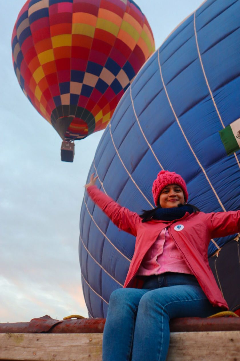 Mujer con los brazos abiertos junto a un globo aerostático en Teotihuacán