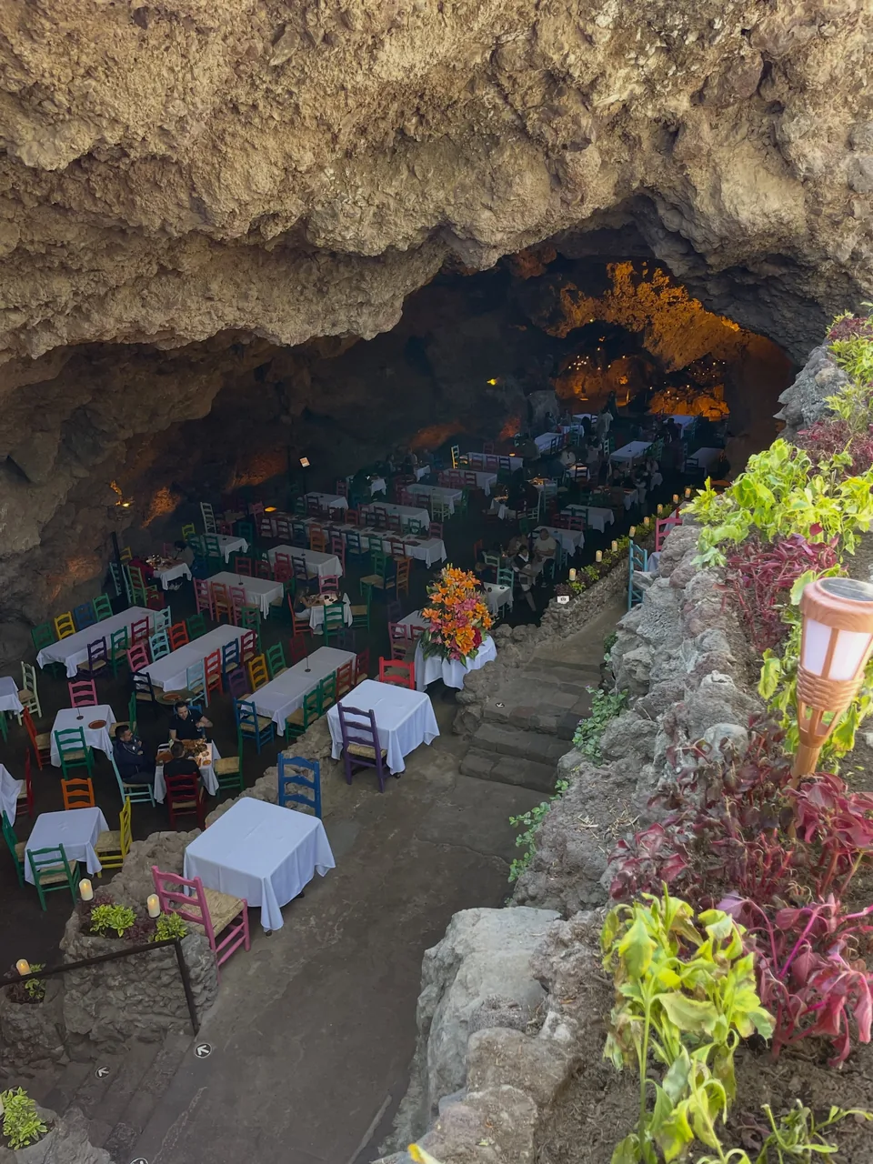 Tables and coloured chairs seen from the rock ledge at La Gruta Teotihuacan